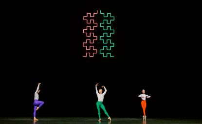 Three ballet dancers on stage in different coloured trousers 