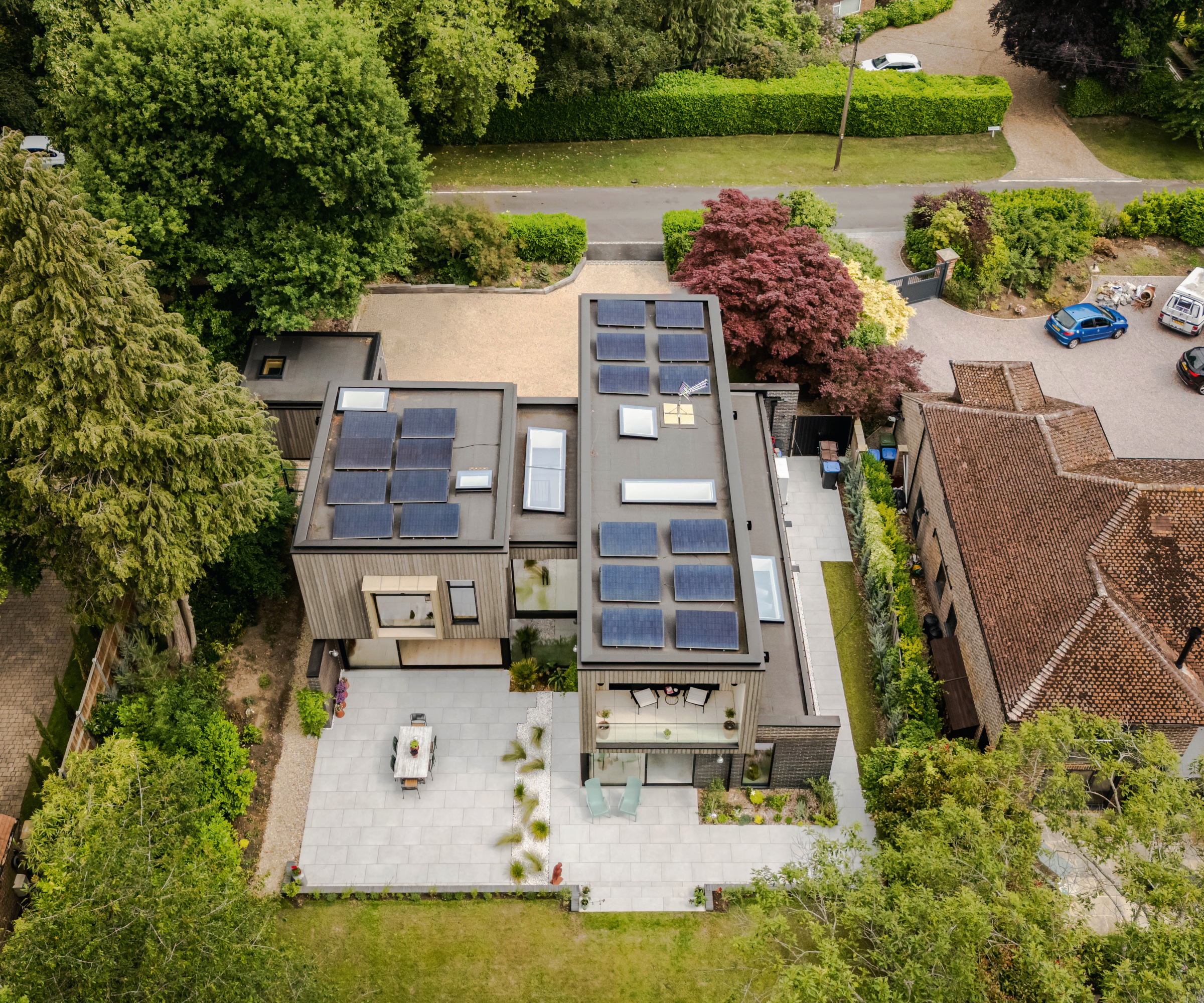 Birds eye view of house with solar panels on the roof, patio and lawn