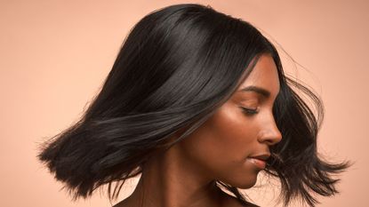 best drugstore shampoo - woman with closed eyes looks over her shoulder with hair blowing in the wind - gettyimages 1329662476