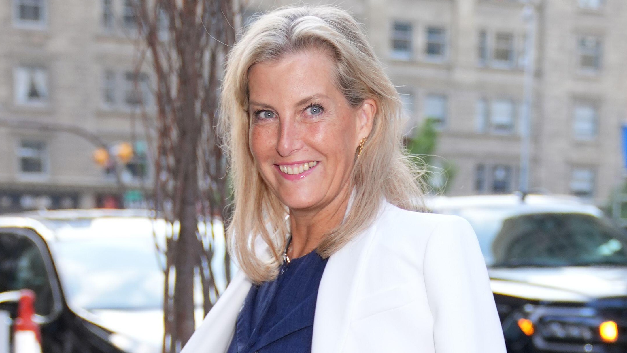 Duchess Sophie smiles as she arrives, wearing a navy blue dress, at the Fairmont Palliser Hotel