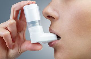 A woman uses an asthma inhaler