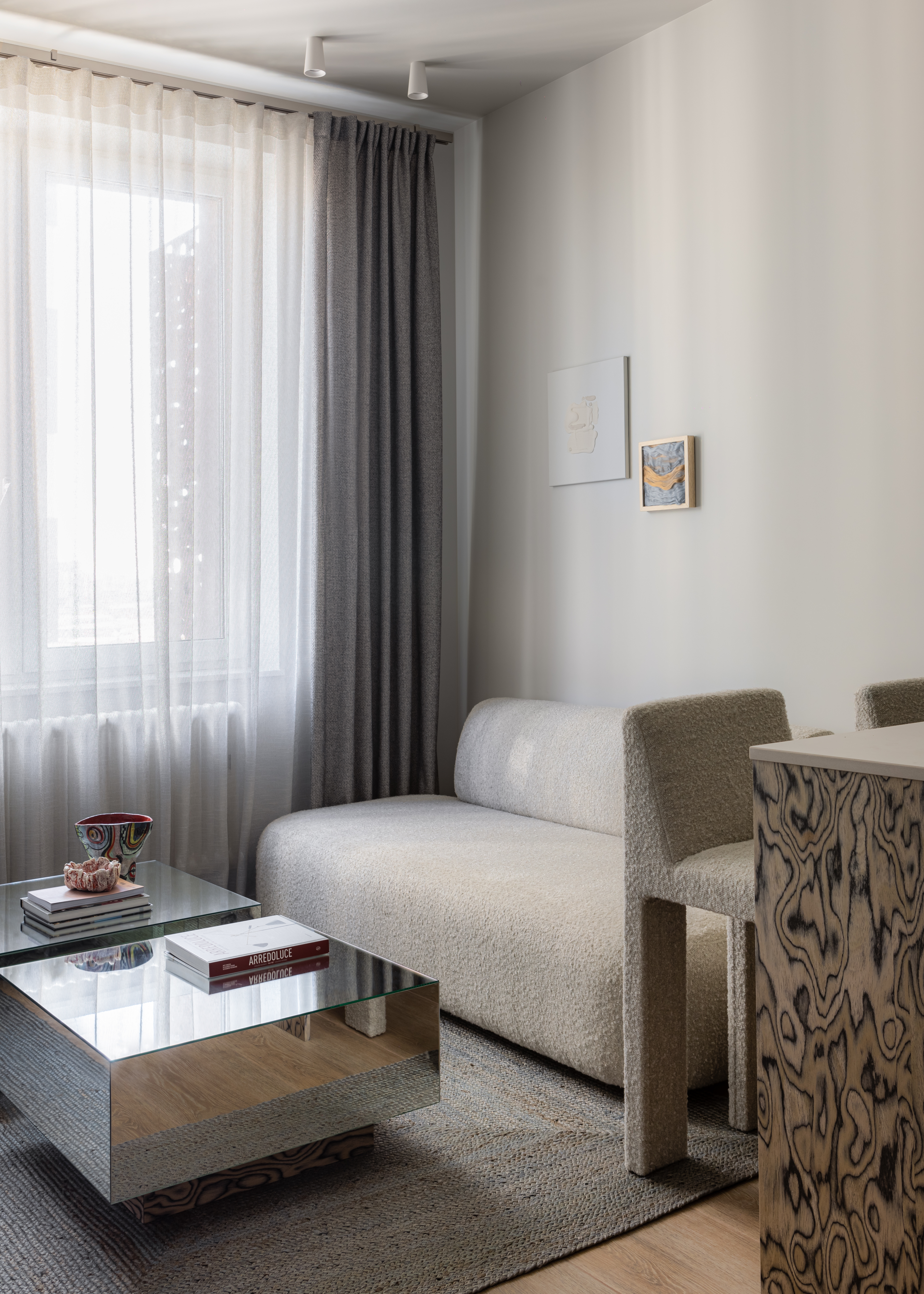 A small living room with a steel coffee table, a neutral couch and a console made in veneer