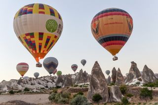 Hot air balloons fly low over hoodoos in Cappadocia, Turkey