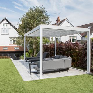 Garden seating area with grey curved sofa and contemporary pergola