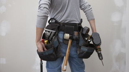 A man wears a tool belt full of tools.