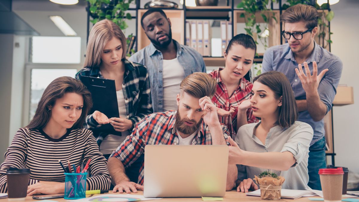 Frustrated team of people in an office looking at a laptop