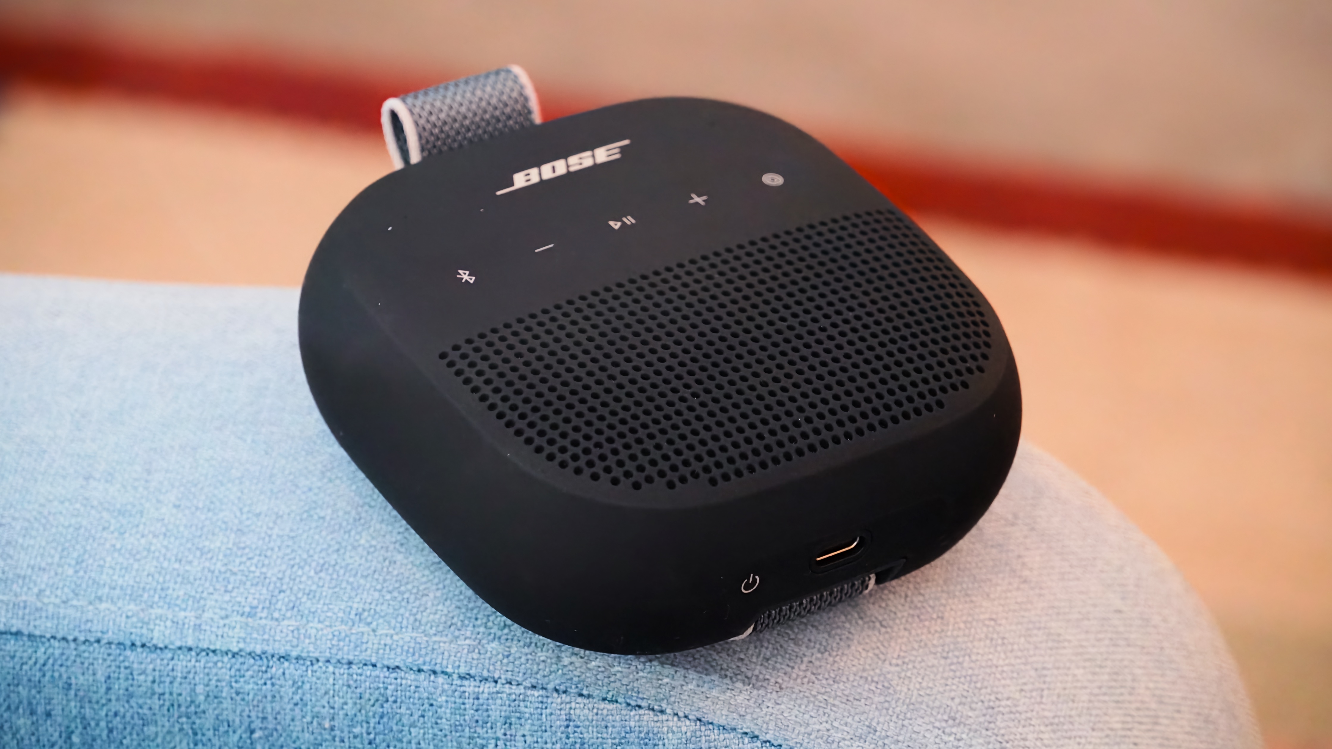 The Bose SoundLink Micro 2 in black on a chair armrest.