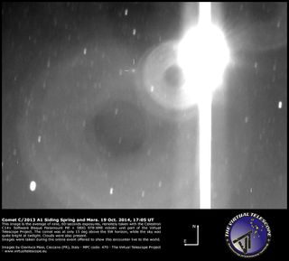 The Comet Siding Spring (C/2013 A1) is seen in crosshairs during an extremely close flyby of Mars (bright, overexposed object) in this view from a remotely operated telescope controlled by the Virtual Telescope Project in Italy on Oct. 19, 2014.