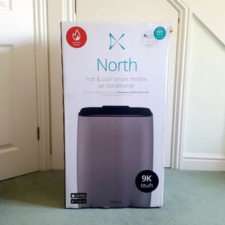 The Duux North 9K Smart Air Conditioner being unboxed in a room with a green carpet and cream walls
