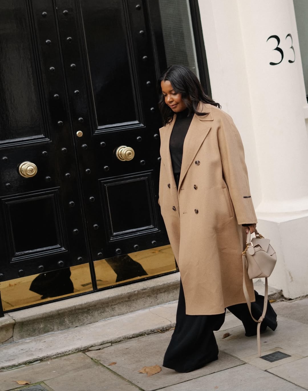 Karina in a beige trench and black outfit