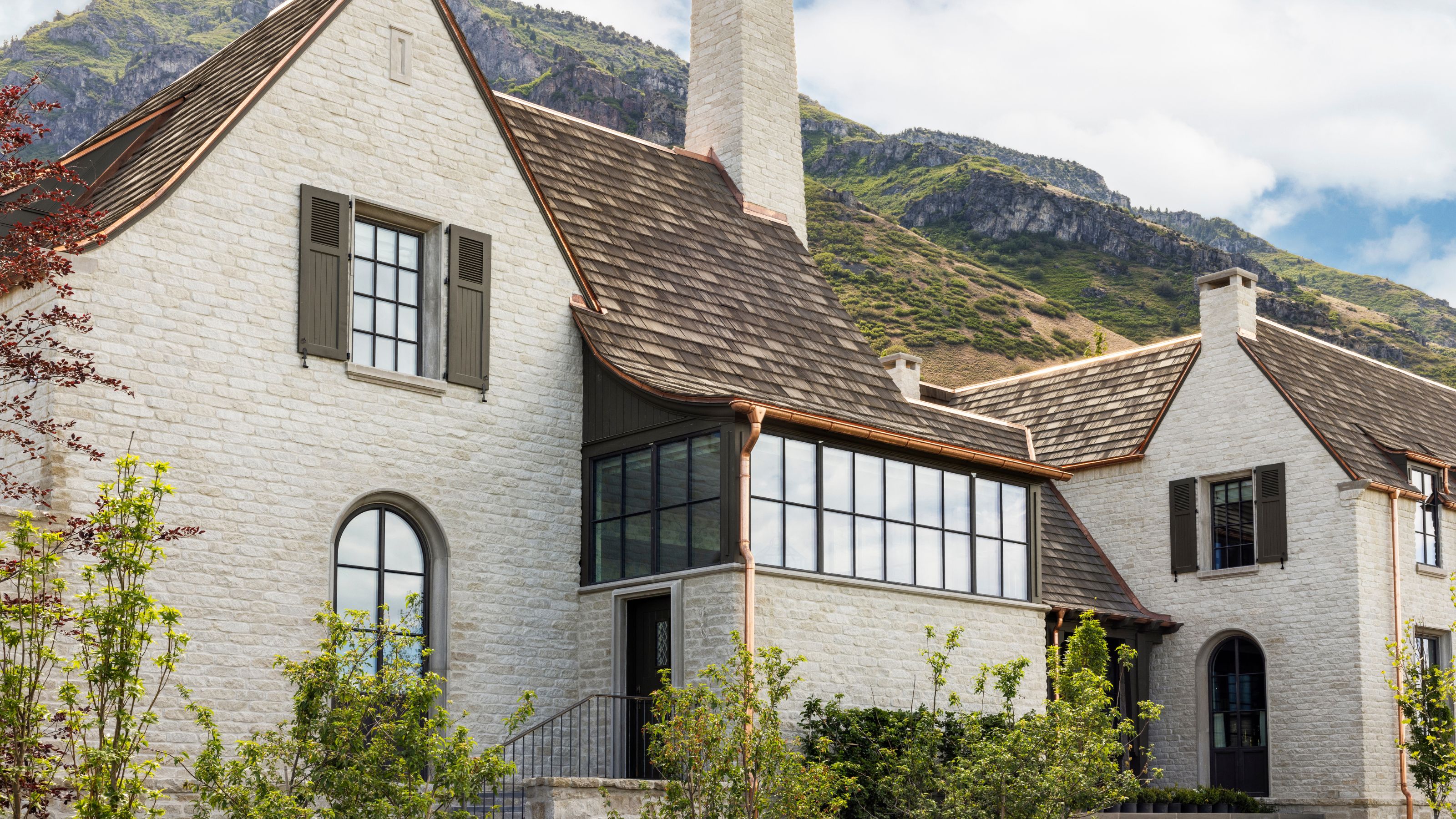 an exterior shot of a large home set beneath a mountain