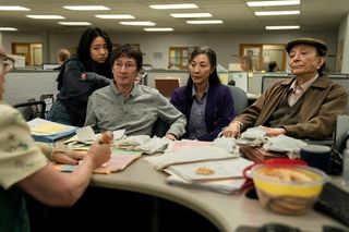 Asian American Family sitting next to each other facing a desk covered in papers