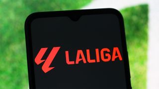 smartphone displaying LaLiga logo in red text in front of part of a football pitch