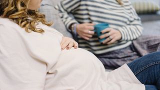 pregnant woman chatting to her friend on the sofa