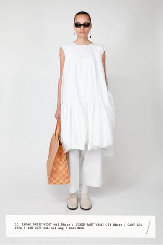 Model wearing a white dress, white pants, tote bag by The Row