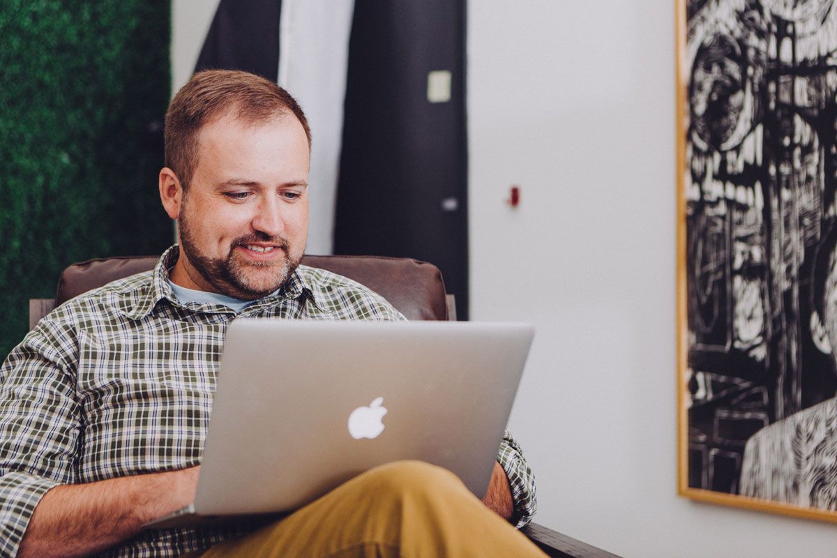 Man sitting on chair with laptop on lap