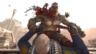 A soldier in blue armor stabs a monstrous, grey-skinned creature in the chest with a combat knife, causing a violent spray of blood in a city ruin.