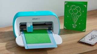 Cricut Joy review; a small craft cutting machine on a wooden table with home made cards