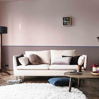 pink wall with wooden flooring and sofa with cushion