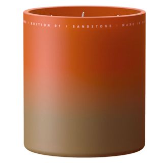 Never Go Alone's sandstone candle in a jar which is a gradient orange color