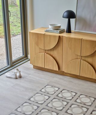 grey wooden effect lvt flooring with patterned tile insert, wooden sideboard and trainers on floor in front of patio doors