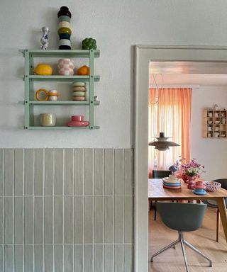 A hallway looking onto a dining room, with a wall-mounted shelf on the wall