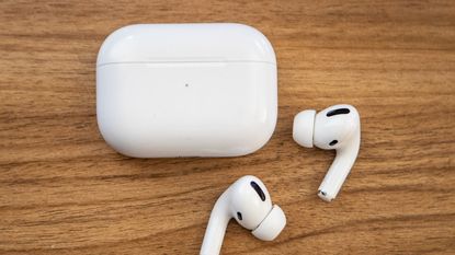 Apple AirPods and case on light wood table