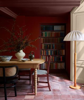 burgundy dining room with terracotta tiles and a painted ceiling and recessed bookshelf nook