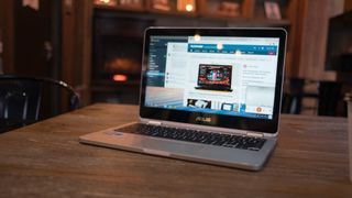 En silverfärgad Asus Chromebook står på ett träbord med TechRadar-hemsidan öppnad på skärmen.