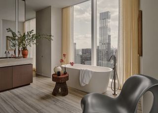 A white tub placed right in front of a large window overlooking Manhattan