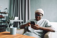Man looks at his phone as he browses the best bank switching offers.