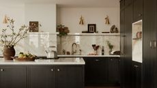 A dark blue kitchen with a beige marble countersplash