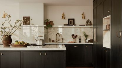 A dark blue kitchen with a beige marble countersplash