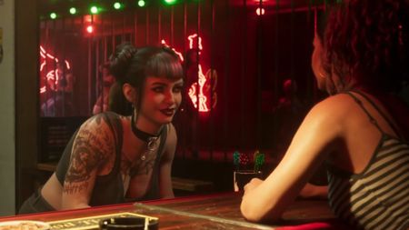 Woman with tattoos leans over and smiles at another woman