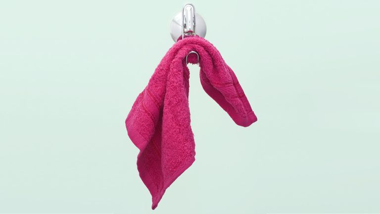 A pink washcloth hanging from a wall.