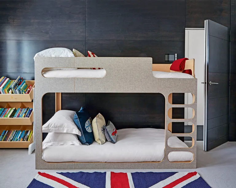 A kids' room with wood-panelled walls, bunk bed and Union Jack rug