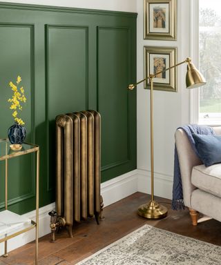 A copper-finish radiator in a living room with green wall