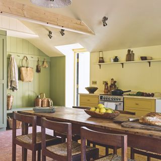 open plan kitchen and dining area with yellow shaker style kitchen units and vintage farmhouse table