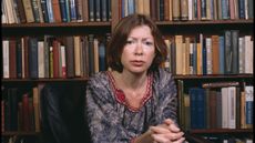 joan didion in front of bookshelves