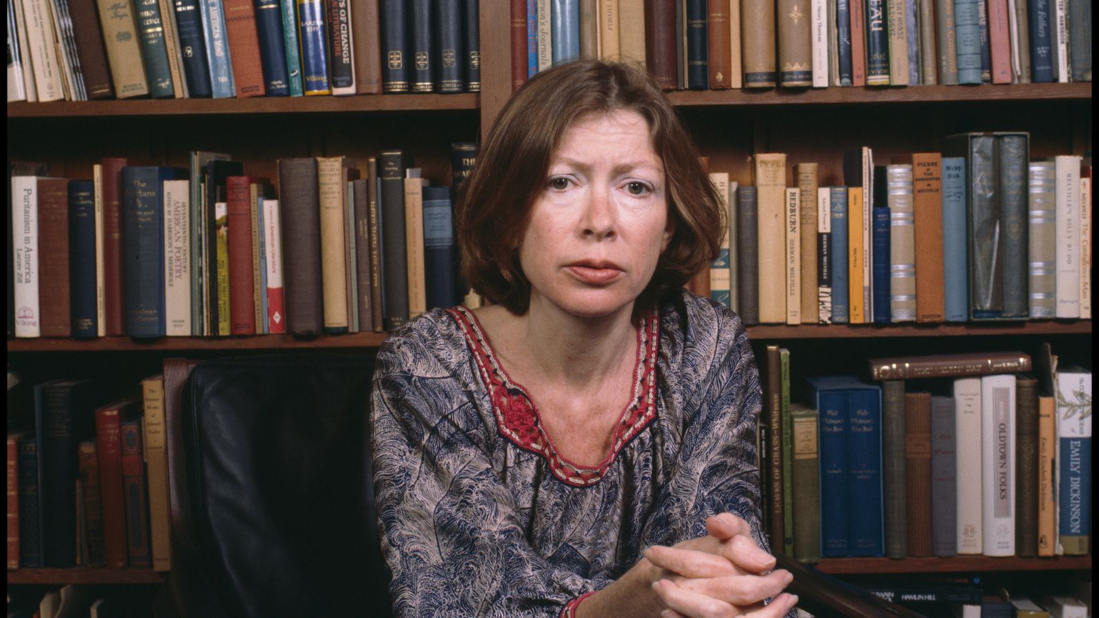 joan didion in front of bookshelves