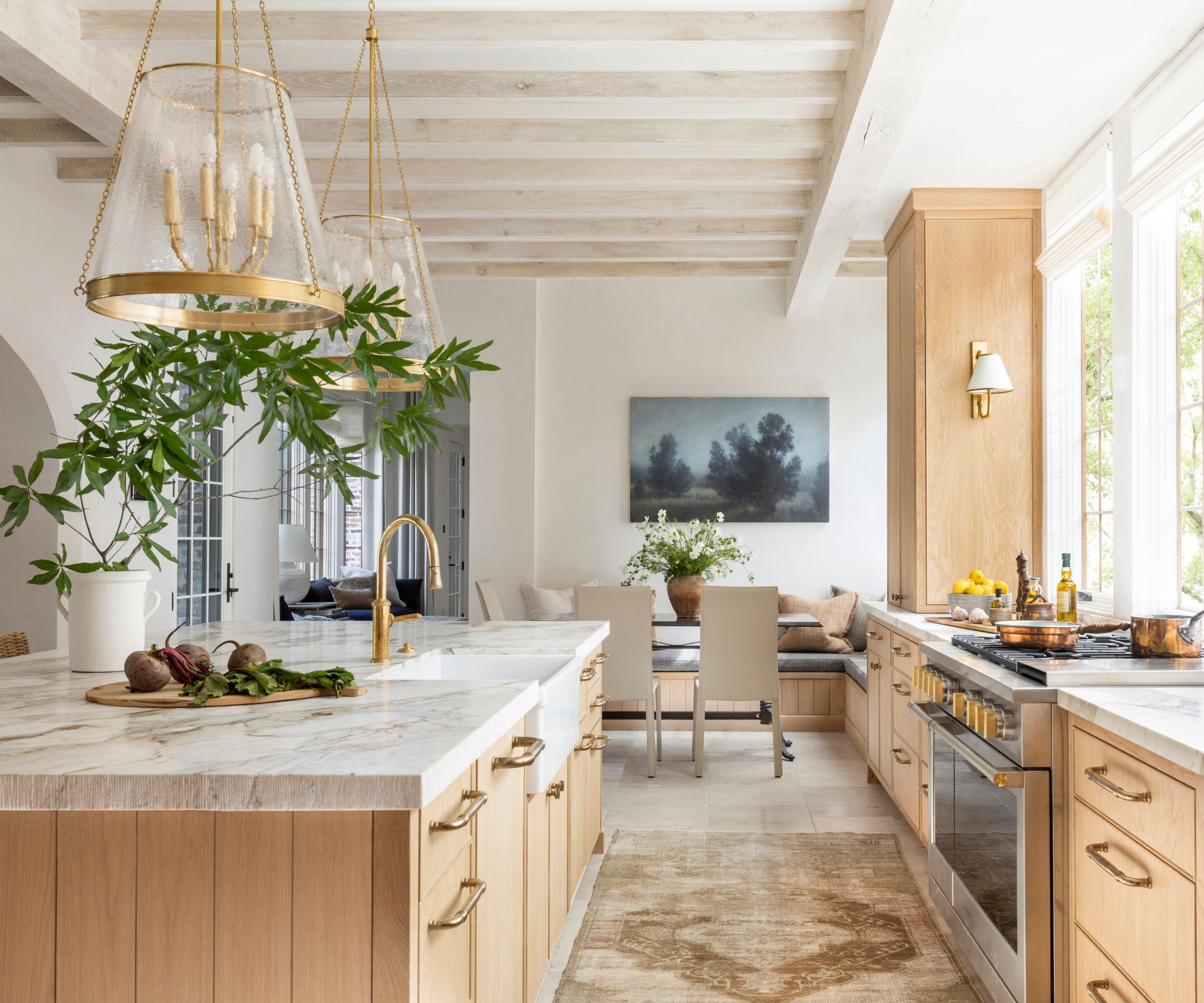 A wooden kitchen with marble counters and a layered lighting scheme