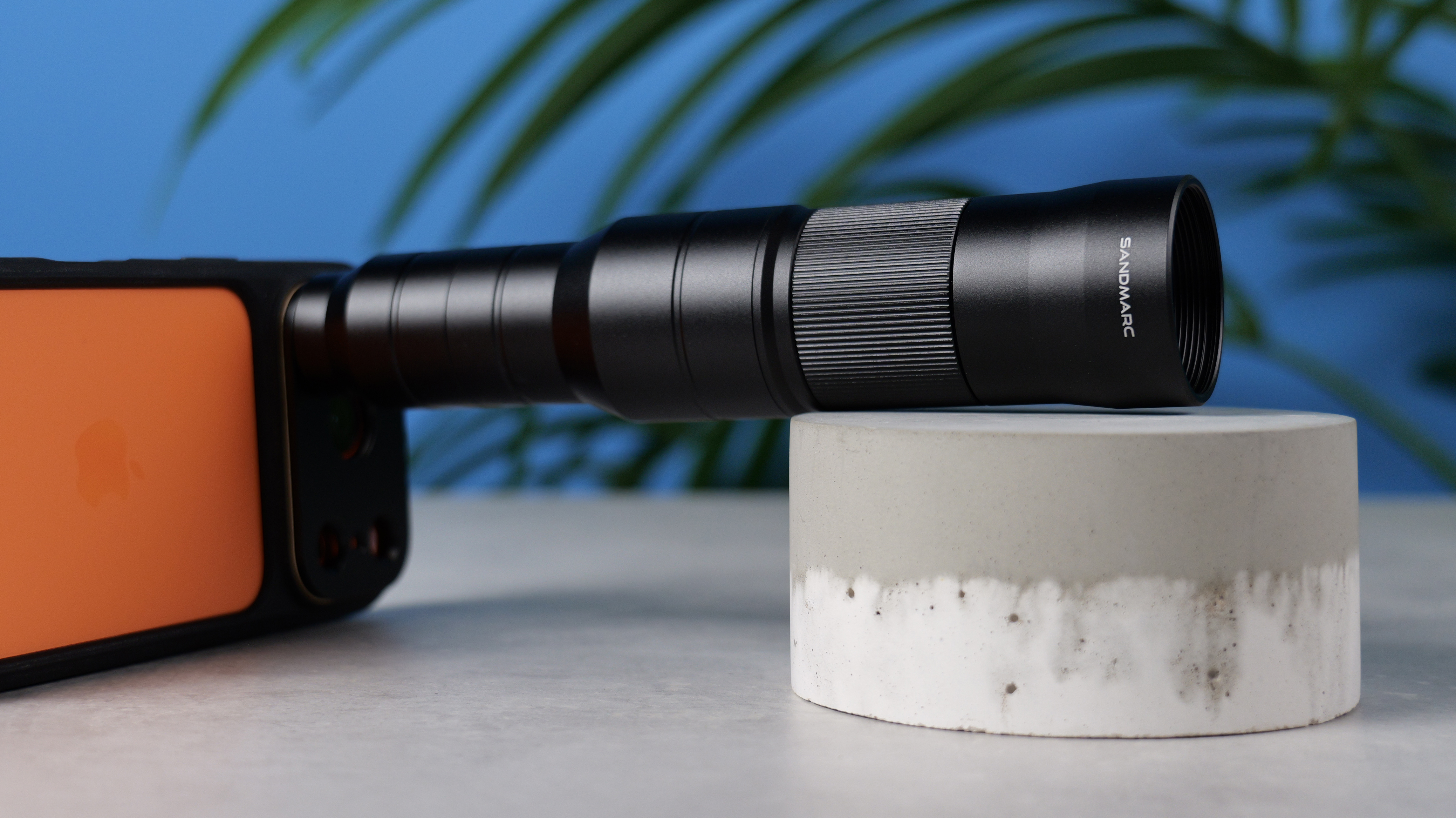 A photo of the Sandmarc 10x lens on an orange iPhone 17 Pro