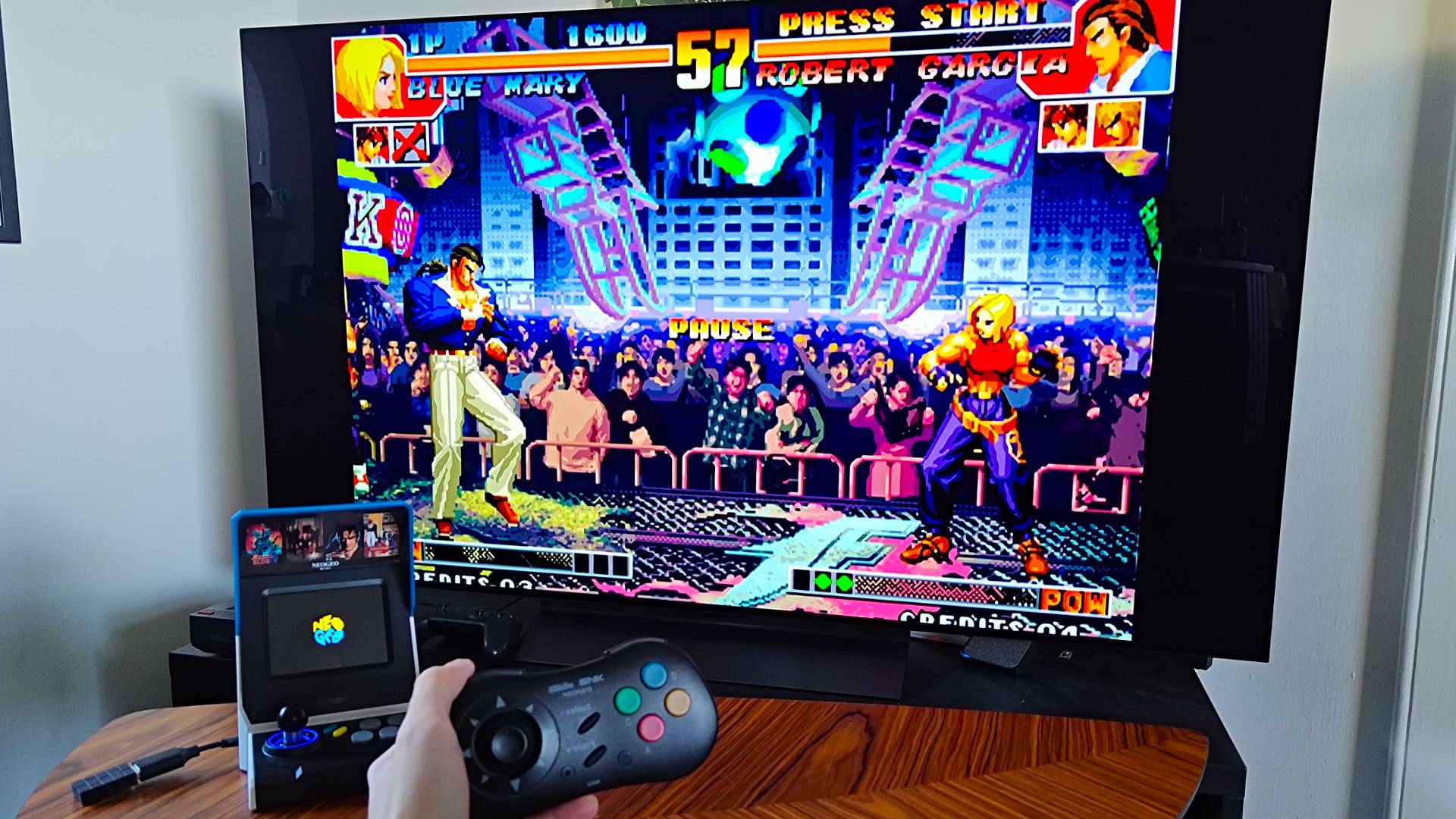 Neo Geo Mini plugged into LG OLED C4 TV with King of Fighters gameplay on screen and hand holding 8Bitdo controller.