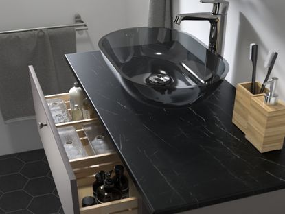 A black bathroom vanity with a glass countertop sink