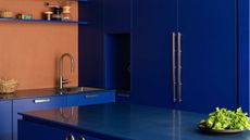 A kitchen with electric blue cabinets and island, and orange walls