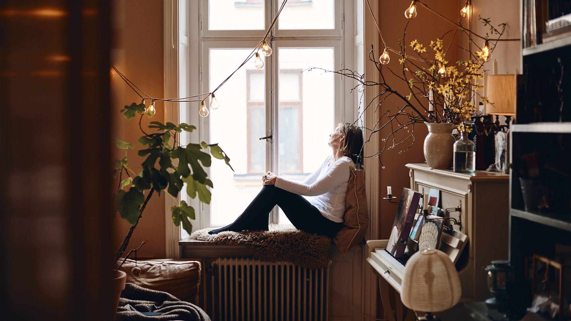 Woman sitting on windowsill in a cozy home