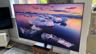 Samsung S95C OLED TV on stand showing image of icebergs onscreen