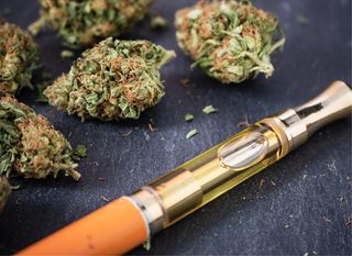 A vape pen next to marijuana.