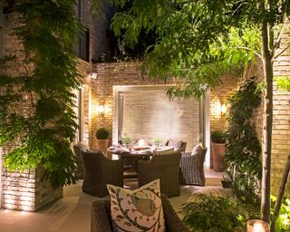 courtyard garden with alfresco dining area lit up at night