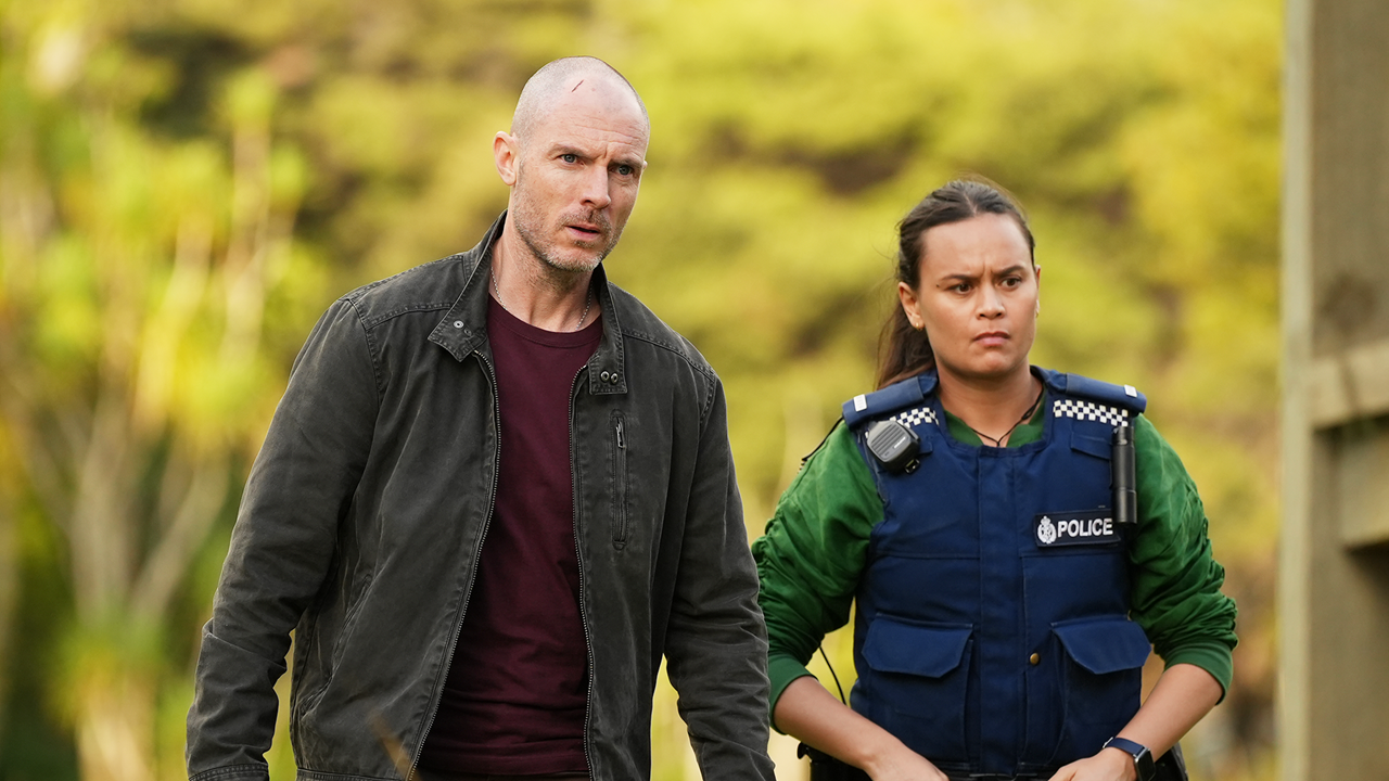 Detective Theo (Richard Flood) and DS Diana Huia (Acushla-Tara Kupe) stand side-by-side with sombre expressions as they search for a lead in their latest case in season 1 of The Gone.